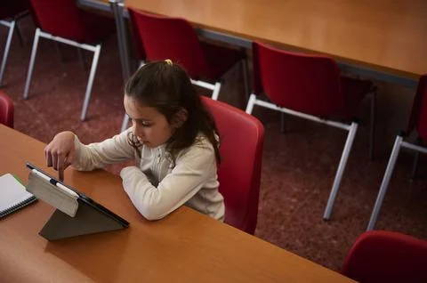 Young Girl Using Tablet at Classroom Desk in a School Library Setting Stock Photos