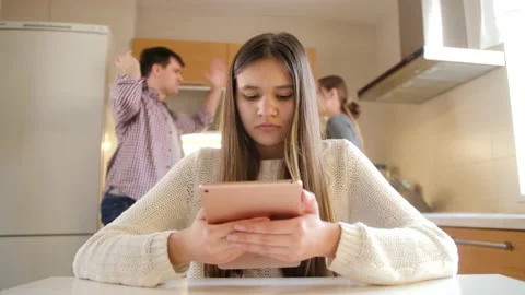 Young girl using tablet computer and ignoring arguing and shouting parents Video stock 155672049
