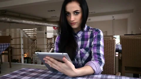 Young girl using tablet pc in the restaurant. She is looking into the camera. Stock Footage 61407821