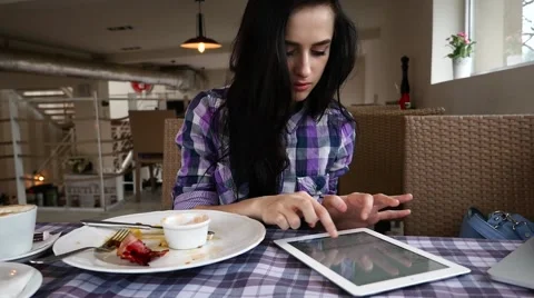 Young girl using tablet pc in the restaurant. She just finished her breakfast. Stock Footage 61408194