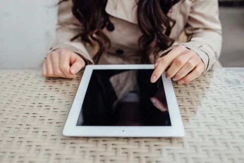 Young girl using tablet pc while sitting outside the cafe. Urban background.  Stock Photos