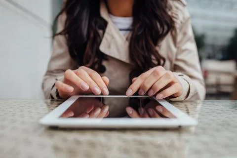 Young girl using tablet pc while sitting outside the cafe. Urban background.  Stock Photos