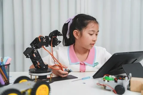 A young girl using a tablet to program a robotic arm. 스톡 사진
