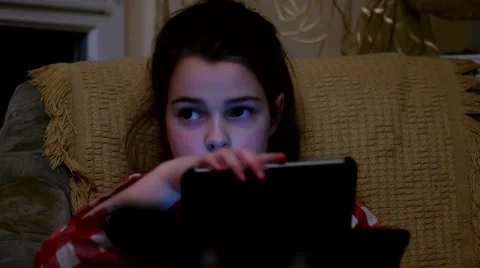 Young Girl Using a Tablet Sitting on a Sofa in the Room Video stock 61002967