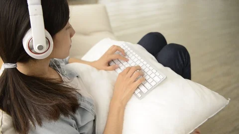 Young girl using wireless keyboard on the couch Видео 93629649