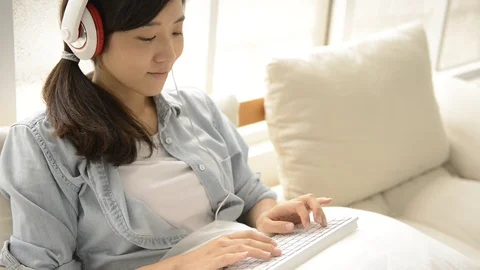 Young girl using wireless keyboard on the couch Видео 93629893