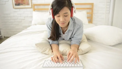 Young girl using wireless keyboard on the bed Видео 93631602