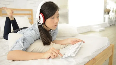 Young girl using wireless keyboard on the bed Видео 93631784