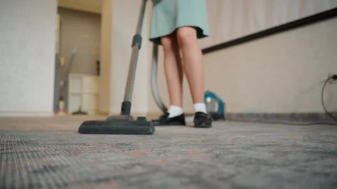 Young girl vacuuming patterned carpet. Canister vacuum cleaning hallway with Stock Footage 336863903
