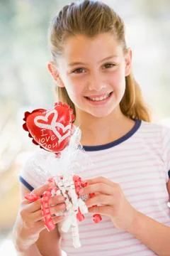 Young girl on Valentine's Day holding love themed balloon smiling Stock Photos
