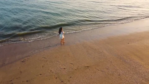 Young girl walking on the beach at sunset Stock Footage