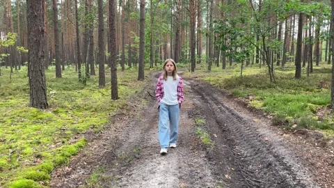 Young girl walking on a path in a pine forest Video stock 308999792