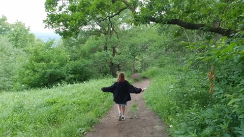 Young girl walking on a path through a green forest Stock Footage 308346253