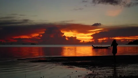 A young girl walks on the beach during sunset Stock Footage
