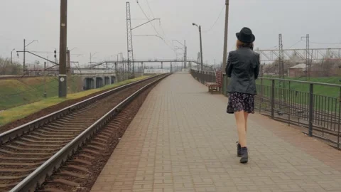Young girl walks on the empty platform of the train station Stock Footage 131215021