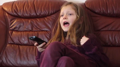 Young girl is watching TV at home Stock Footage