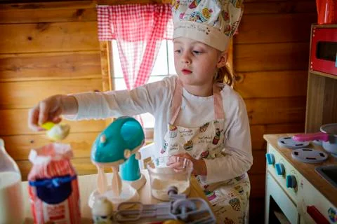 Young girl in wendy house pretending to cook in kitchen Stock Photos