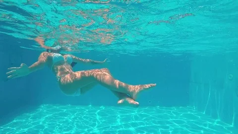 Anonymous young woman in bikini lounging in pool - a Royalty Free