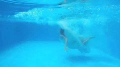 Young girl in white wedding dress jumping into the swimming pool. Stock Footage