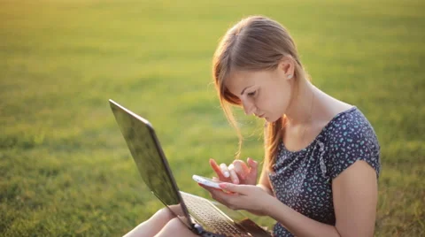 Young girl working on a laptop while sitting on a green lawn Stock Footage 52582484