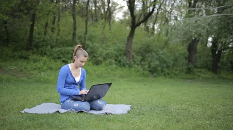 Young girl working on a laptop while sitting on the lawn Video stock 62844907