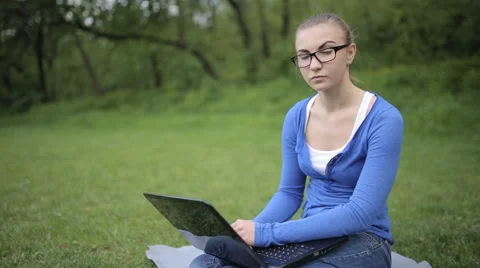 Young girl working on a laptop while sitting on the lawn Video stock 62844930