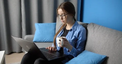 Young girl working on laptop while drinking coffee at home Stock Footage 123561867