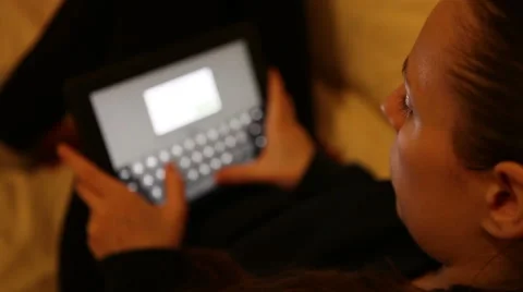 Young girl working on a tablet while lying on the couch Stock Footage 58809118