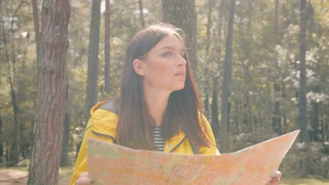 Young girl in yellow jacket with backpack walks in woods, looking around Stock Footage 147063351
