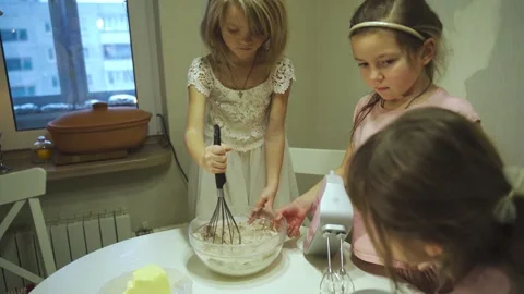 Young girls engage in creative baking fun in a cozy kitchen setting Stock Footage 295989525