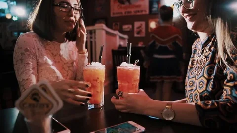 Young girls in glasses tastes cocktails sitting at bar cafe table Stock Footage