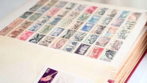 Young girl's hand scrolls through an album of postage stamps Stock Footage 110423897