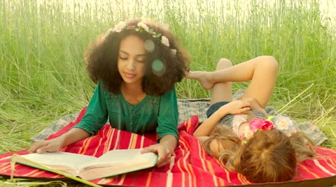 Young girls lying on cover and reading Stock Footage 64769853