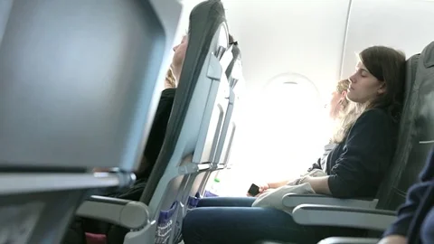 Young Girls Sleeping Near Aircraft Window during a day's flight in bright sunlig Stock Footage 85243145