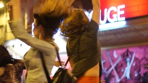 Young girls tourists have fun at night Paris bright neon Moulin Rouge cabaret Stock Footage