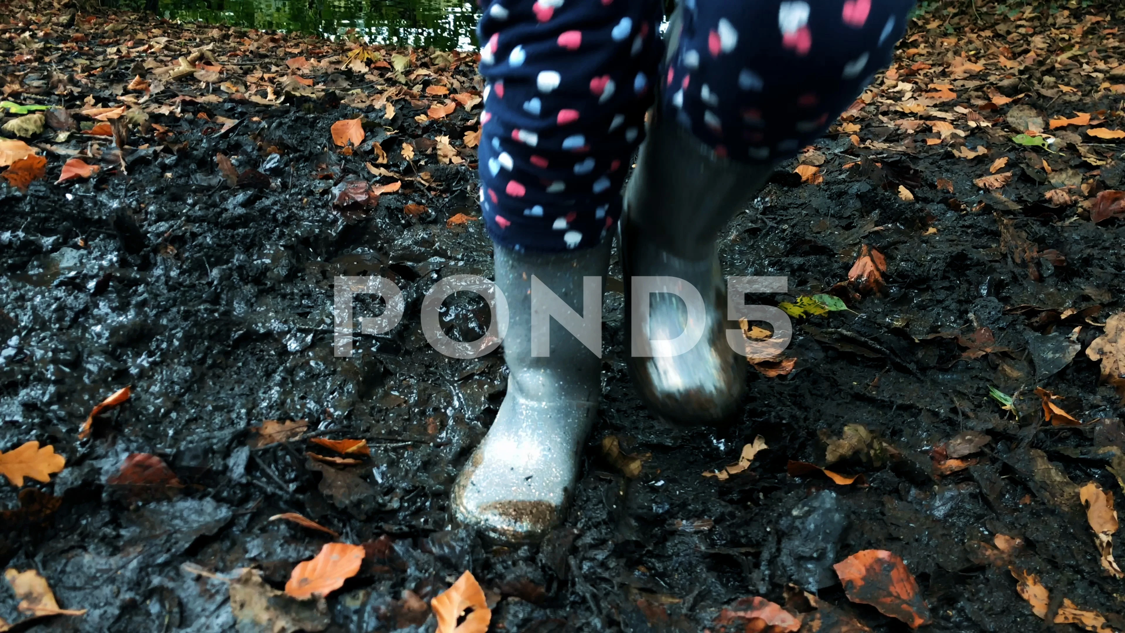 Young girls with wellies playing in a muddy puddle