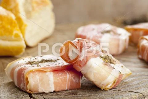 Young goat's cheese wrapped in bacon with herbes de Provence Stock Photos
