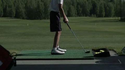 Young golfer practices his golf swing on driving range, view from side Stock Footage 95133407