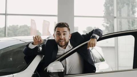 Young good looking man is showing thumb up and the keys of his new car looking Stock Footage 91832263