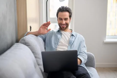 Young good-looking man is using a laptop for video connection, making real call Foto stock