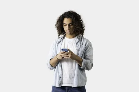 Young good looking man using mobile phone on isolated white background. Stock Photos