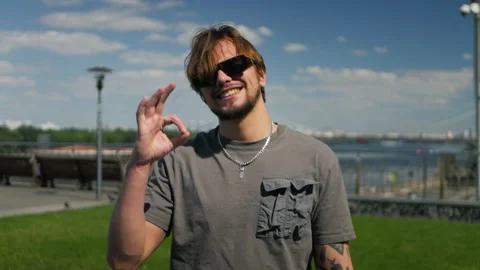 Young good-looking white man showing okay sign in slow motion outdoors Stockbeeldmateriaal 197637763