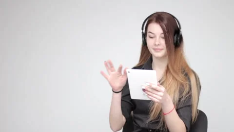 Young good looking woman using white tablet listens music in wireless headphones Stockbeeldmateriaal 137540722