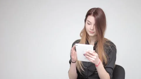 Young good looking woman using white tablet and fixing hair on light background Stockbeeldmateriaal 137540819