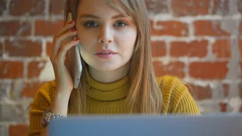 Young gorgeous smiling female talking on mobile phone and using laptop Stock Footage 72047426