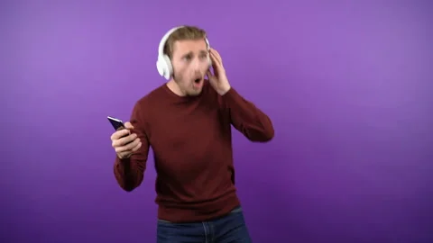 Young graceful guy dynamically dancing and sings loudly on isolated purple Stock Footage 149040439