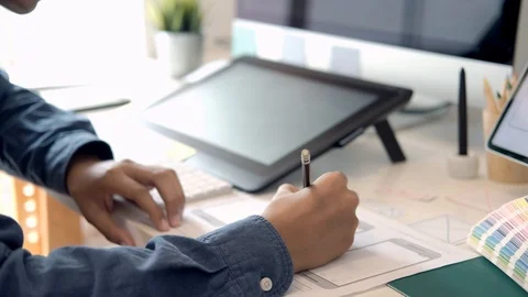 Young graphic designer drawing, writing and using pen with digital tablet com Stock Footage 112983906