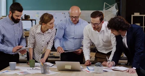 Young group of business workers standing around a table with documents, charts Stock Footage 82446207
