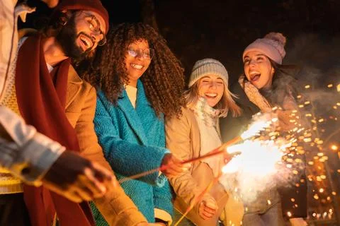 Young group of friends having fun together at night outdoors winter party Stock Photos