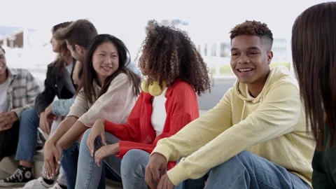 Young group of happy students sitting together outside while hanging out Stock Footage 255913396